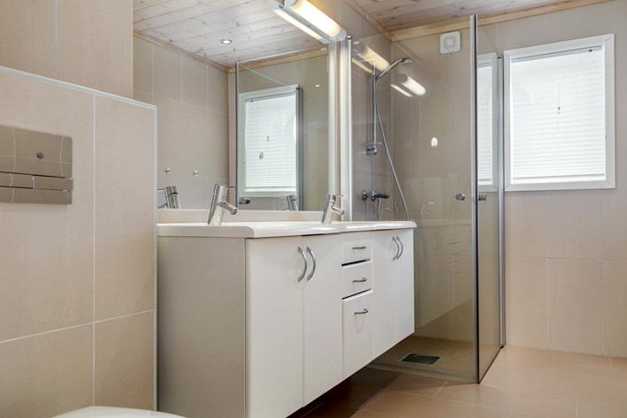 Badrum med sandfrgat kakel och klinkers, dubbla handfat och dusch med glasdrrar